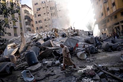 Un hombre camina junto a los escombros de un edificio colapsado en Gaza tras el ataque del Ejército israelí, este sábado.  