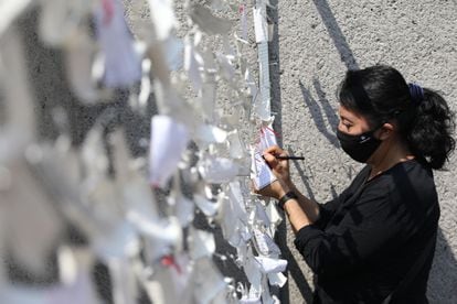 Una mujer coloca un mensaje dedicado a las personas fallecidas por la covid-19, en un mural en Ciudad de México el pasado sábado.