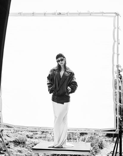 La actriz, con chaqueta de piel cruzada, falda larga en satén, brazaletes en madera y latón, y gafas de sol, todo de Saint Laurent by Anthony Vaccarello.