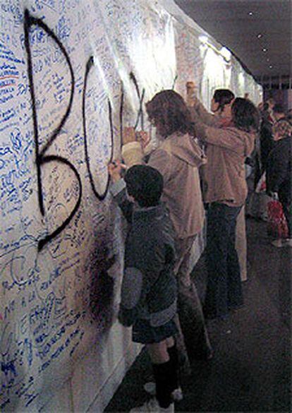 Aficionados escriben mensajes contra la violencia en un mural que había sido pintado por los <i>boixos</i>.