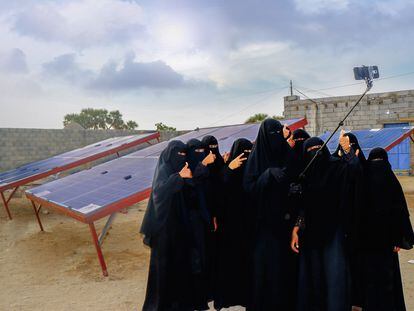 Iman Haddi y sus compañeras se toman una foto con el móvil delante de los paneles solares que han instalado.
