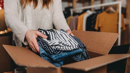 A millennial woman is preparing the shipment of some clothes in her new online shop. She's the owner of an online thrift store. New small business concept.