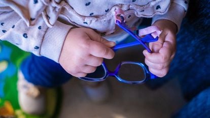 Salma, una niña de dos años, coge sus gafas que sus padres están pagando a plazos porque suponen el 82% del sueldo que entra en casa.