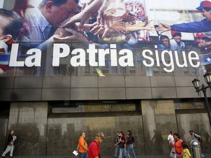 Ciudadanos de Caracas caminan este miércoles frente a un cartel que retrata a Chávez y Maduro cerca de la Asamblea Nacional.