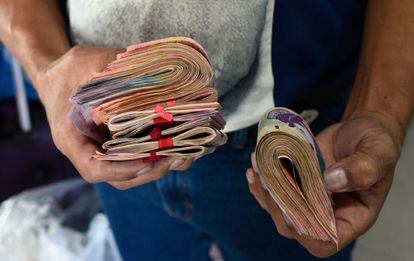 Un hombre sostiene dinero para comprar un billete de autobús en Caracas. El 15 de enero entró en vigor una medida anunciada por Maduro para aumentar un 300% el salario mínimo, de 4.500 a 18.000 bolívares. Así, este pasó de 5,22 dólares a 20,9 dólares, según la tasa oficial de cambio, mientras que en el cambio paralelo se quedó en seis dólares al mes.