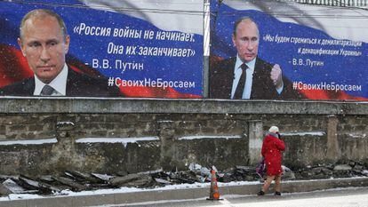 Una mujer para por delante de un cartel en Crimea que dice: "Rusia no empieza las guerras, Rusia las termina".