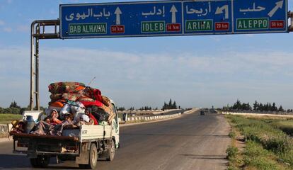 Unos ciudadanos sirios viajan con sus pertenencias por la autopista entre Damasco y Aleppo a la altura de Idlib mientras huyen de posibles ataques aéreos del régimen y sus aliados en la zona. La violencia en esta región ha desplazado a más de 150.000 personas la semana pasada, según la ONU.