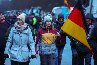 Una persona sostiene una bandera alemana mientras los agricultores protestan contra el recorte de los subsidios fiscales a los vehículos en Berlín