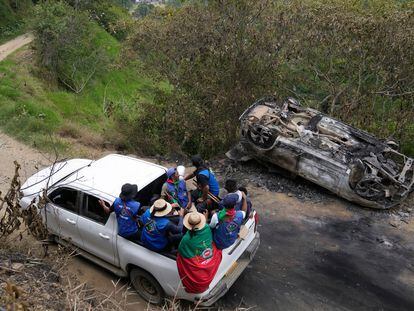Miembros de la Guardia Indígena pasan junto a un vehículo que incendiado por rebeldes del Estado Mayor Central (EMC), en Toribio, Colombia, el 19 de marzo.