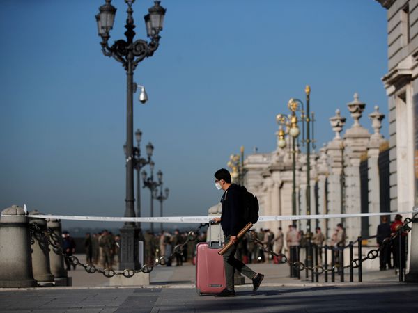 GRAF7672. MADRID, 09/10/2020.- Un joven con su maleta pasa ante el Palacio Real de Madrid. El Gobierno español aprobó hoy la declaración del estado de alarma en Madrid para evitar la expansión del coronavirus, según comunicó el jefe del Ejecutivo, Pedro Sánchez, a la presidenta de la región de Madrid, Isabel Díaz Ayuso.EFE/ Juan Carlos Hidalgo