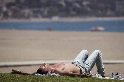 Un hombre disfruta del buen tiempo en la playa de la Malagueta, en M&aacute;laga.