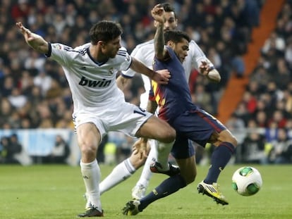 Alves protege el balón entre Xabi y Arbeloa.