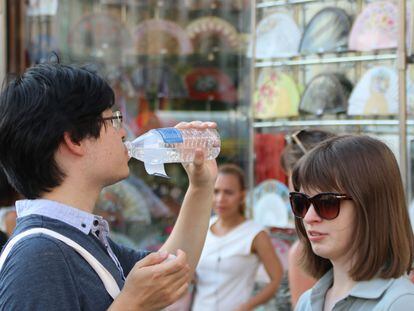 Un turista bebe una botella de agua en la Puerta del Sol en Madrid, en plena ola de calor en julio de 2022.