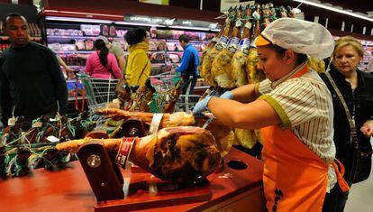 Una empleada cortando jam&oacute;n en un supermercado.