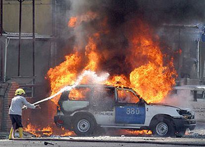 Un bombero intenta apagar un coche policial en llamas tras la explosión de un artefacto en Bagdad.
