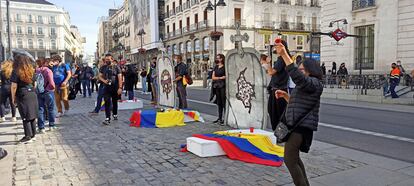 Los manifestantes despliegan dos lápidas en la Puerta del Sol de Madrid para protestar por la violencia de Estado y policial en su país, Colombia.