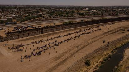 Cientos de migrantes esperan cerca del muro fronterizo, después de cruzar el río Bravo, en Ciudad Juárez.