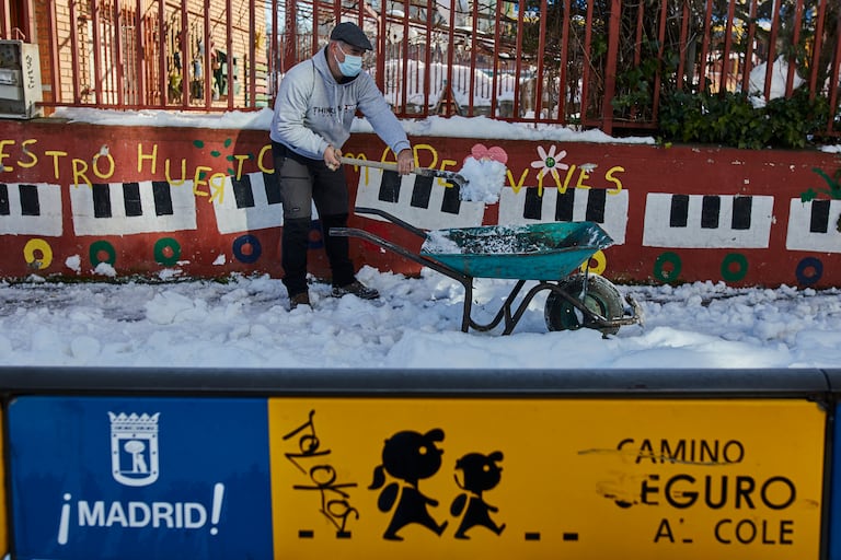 Un familiar colabora en la limpieza del hielo y la nieve en las inmediaciones del colegio Amadeo Vives tras la nevada.