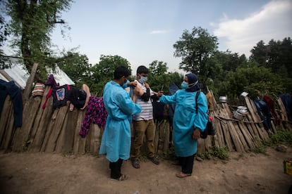 Dos sanitarios administran vacunas de AstraZeneca en Minnar, localidad la norte de Srinagar, India, este jueves.