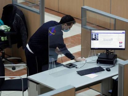 Un hombre desinfecta uno de los puestos dela sede de la delegación de Hacienda de Guzmán el Bueno en Madrid. 