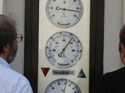 Dos homes miren un termòmetre al carrer.