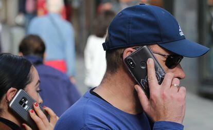 Dos personas hablan por el móvil en el centro de Madrid.