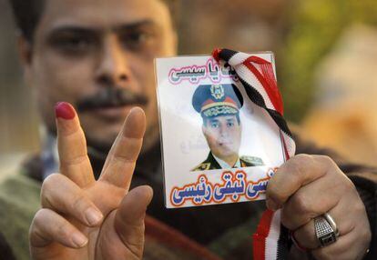 En egipcio muestra la tinta en su dedo coraz&oacute;n y una foto del general Al Sisi en El Cairo.