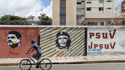 Un hombre pasa en su bicicleta frente a un mural con la imagen del presidente de Venezuela, Nicolás Maduro, y de Ernesto "Che" Guevara, en Caracas.