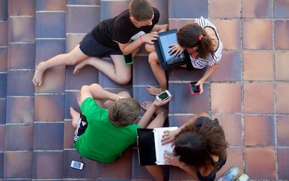 Niños y niñas con ordenadores y dispositivos electrónicos.