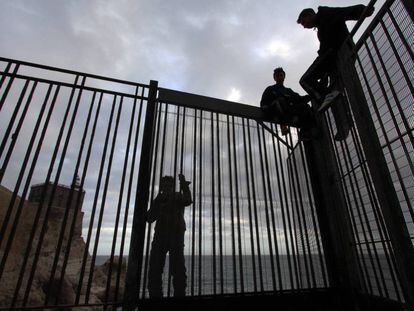 Jóvenes marroquíes, en la verja del espigón de Melilla.