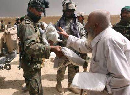 Un soldado afgano entrega, ante un militar estadounidense, bolsas con ayuda humanitaria a un anciano de Ghazni.