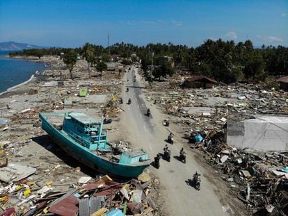 Los aldeanos circulan en motocicletas cerca de un barco arrastrado a tierra por el tsunami en Palu, el 1 de octubre.