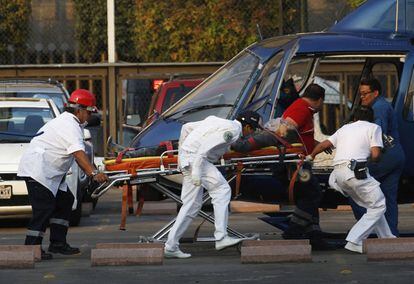 Personal paramédico transporta en camilla a una herida junto a un helicóptero de emergencias.