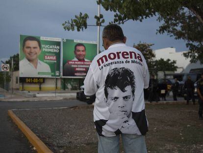 Un simpatizante de Morena frente a propaganda del PRI en Mérida, Yucatán.