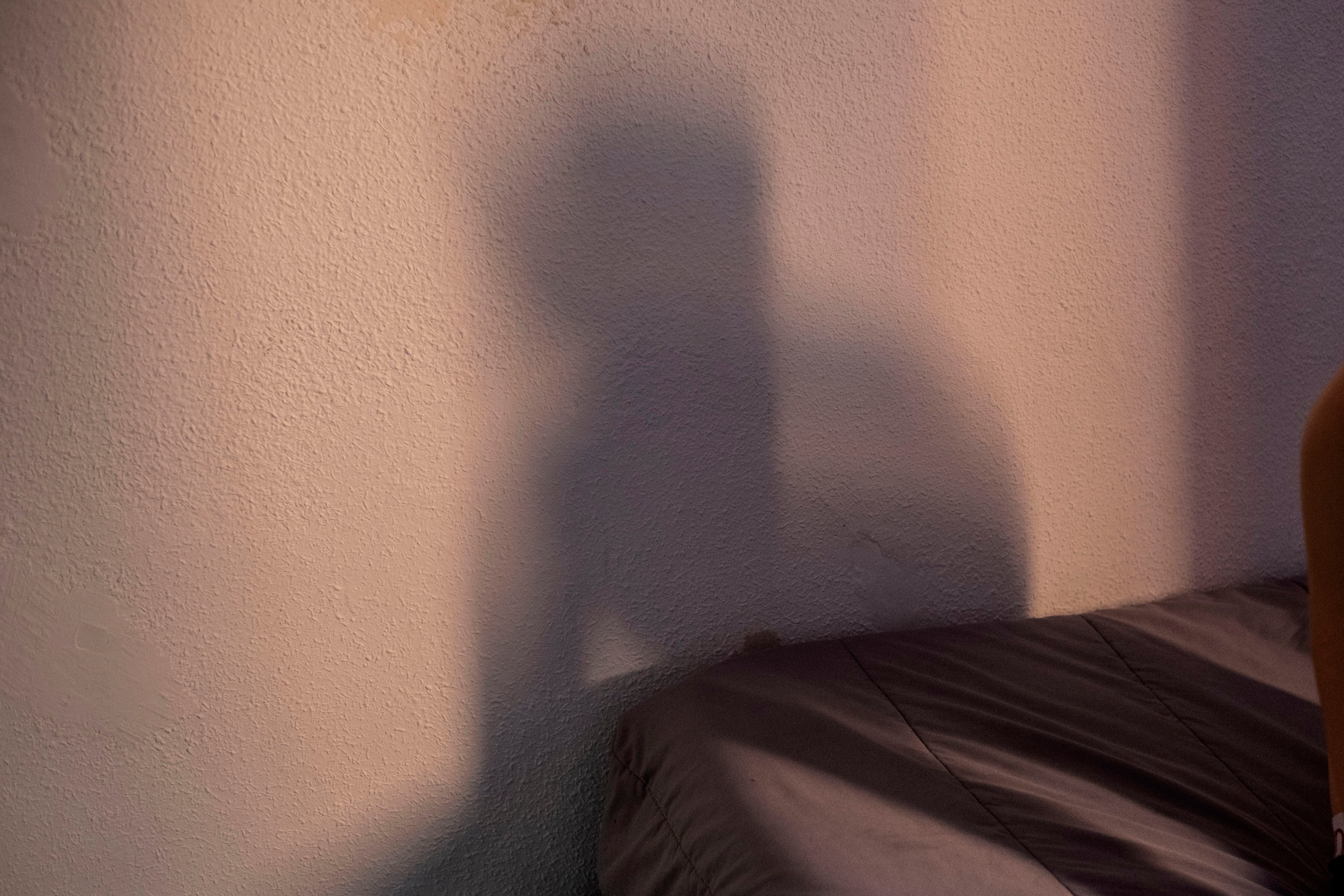 La sombra de pablo se proyecta en la pared a última hora de la tarde.