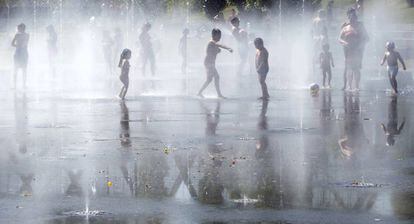 Unos niños juegan con el agua en una de las fuentes de Madrid Río.