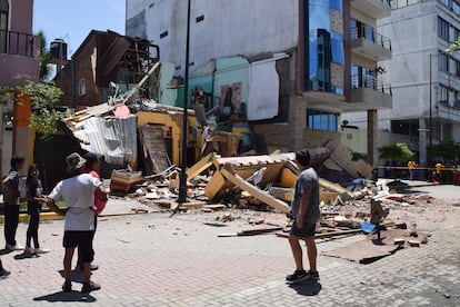 Al menos 13 personas han muerto este sábado como consecuencia de un seísmo de magnitud 6,5 registrado en la provincia de Guayas, en la costa de Ecuador. En la imagen, vecinos de la ciudad de Machala junto a un edificio que cayó durante el temblor. 