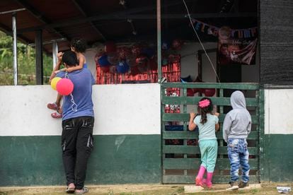 Un hombre y un grupo de niños observan el restaurante comunitario del Espacio Territorial de Capacitación y Reincorporación (ETCR) en Icononzo, el 17 de noviembre.