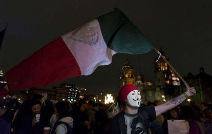 Un hombre enmascarado ondea una bandera en el Zócalo de México.