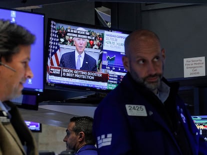 Corredores de la Bolsa de Nueva York trabajan mientras Biden ofrece un discurso sobre la nueva variante de covid en la televisión este lunes.