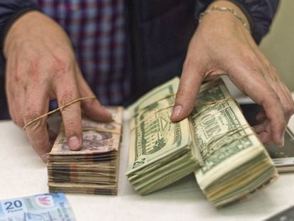 Un hombre sostiene fajos con billetes de dólares y pesos mexicanos, en una casa de cambio monetario en Laredo (EE UU), en una imagen de archivo.