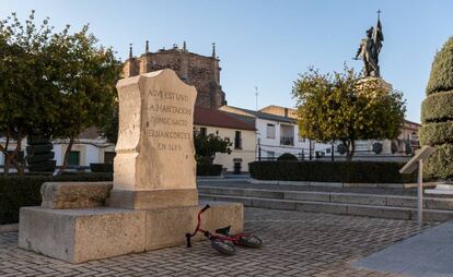 Monolito que indica la ubicación de la casa natal de Hernán Cortés y al fondo su estatua, en Medellín (Badajoz).