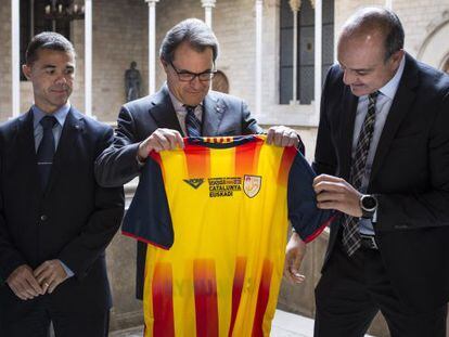 Artur Mas (dentro) recibe una camiseta de la seleccion catalana de futbol.