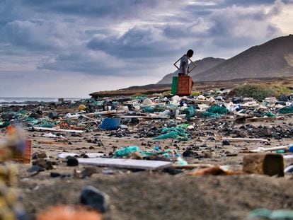 Un hombre recoge plástico y basura de una playa.