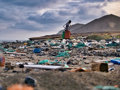 Un hombre recoge plástico y basura de una playa.