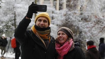 Dos personas se toman una foto en el Retiro, en Madrid, durante la nevada.