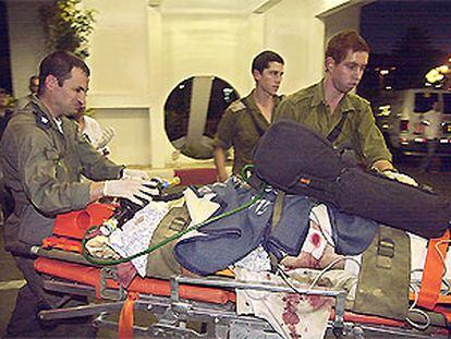 Médicos militares israelíes transportan en una camilla a una de las víctimas del atentado palestino.