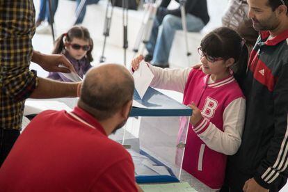Una niña introduce la papeleta de su padre en una mesa electoral en Galicia