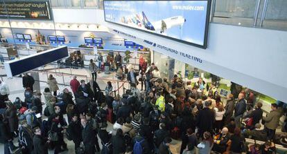 Varios pasajeros de Malev esperan a recibir informaci&oacute;n en el aeropuerto de Budapest.