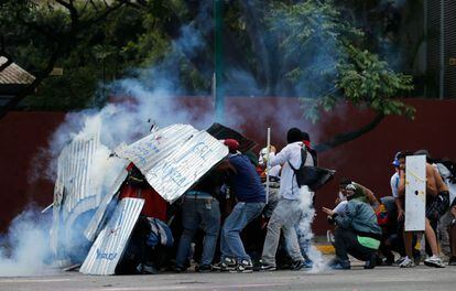 Los botes de gases lacrimógenos lanzados por la Guardia Nacional Bolivariana alcanzaron a los manifestantes que tratan de protegerse con escudos improvisados durante los enfrentamientos en Caracas.